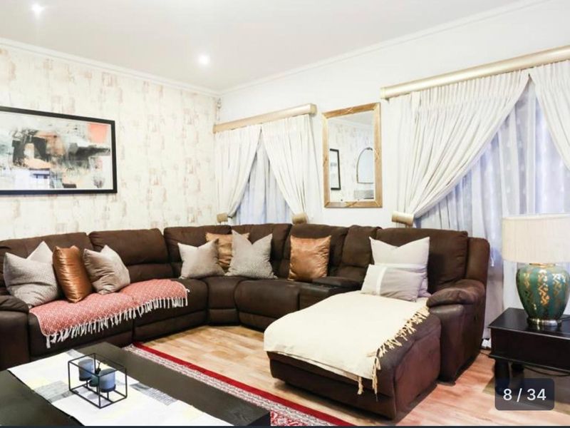 A comfortable living room featuring laminate flooring and recessed downlighting, providing a neutral base for interior design.