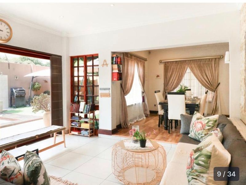 Open-plan living and dining area featuring tiled and wooden flooring, with large sliding doors providing seamless access to the outdoor patio space.