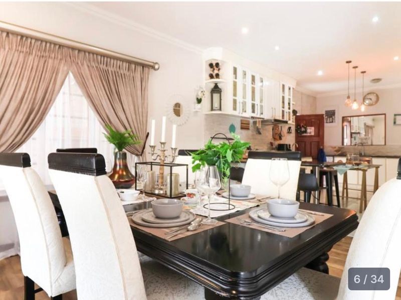 An open-plan dining and kitchen area featuring modern cabinetry, recessed lighting, and neutral finishes, creating a cohesive and functional living space.