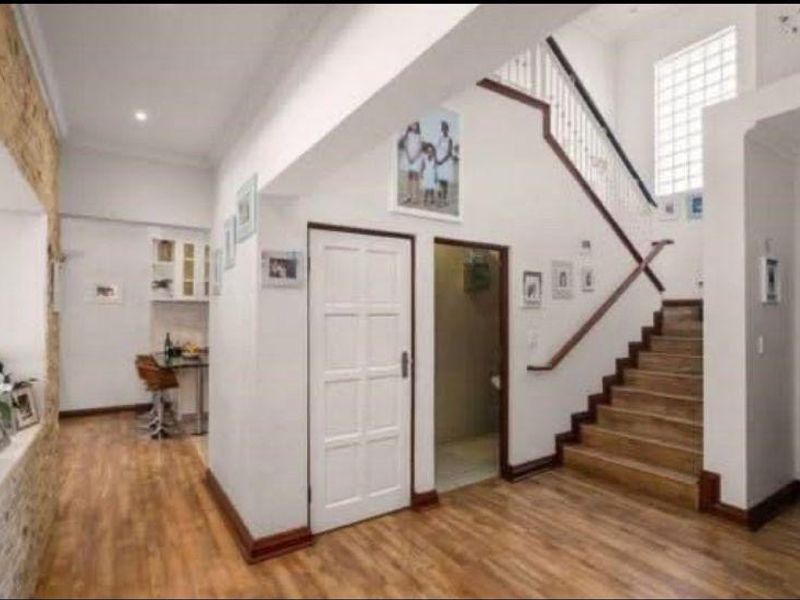 Welcoming entrance hall featuring a staircase with a wooden handrail, laminate flooring, and a decorative stone feature wall.