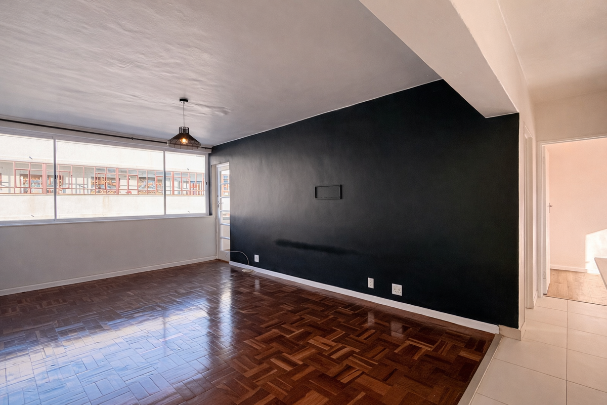 Spacious living area featuring polished parquet flooring, a striking black feature wall, and large windows providing ample natural light.