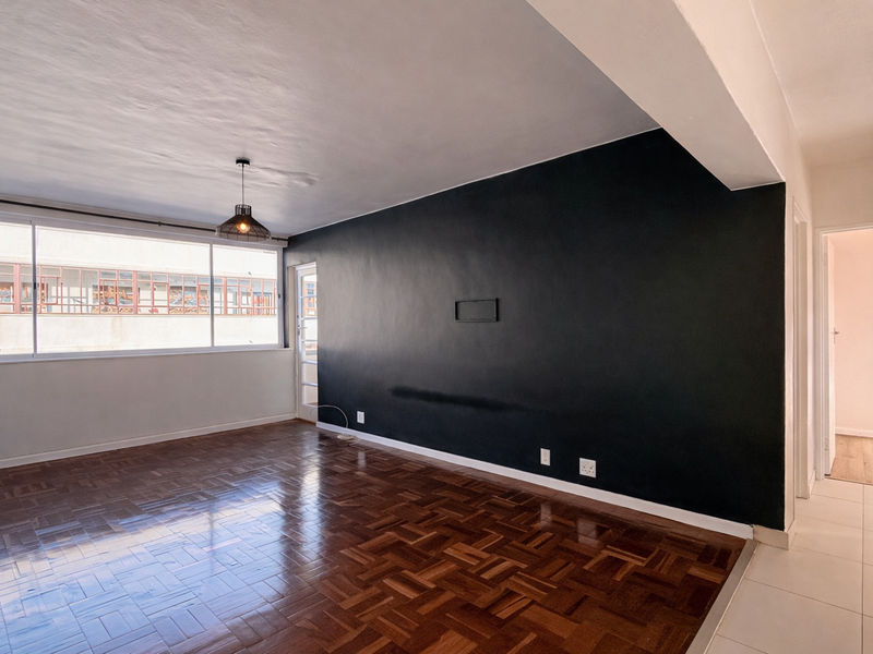 Spacious living area featuring polished parquet flooring, a striking black feature wall, and large windows providing ample natural light.