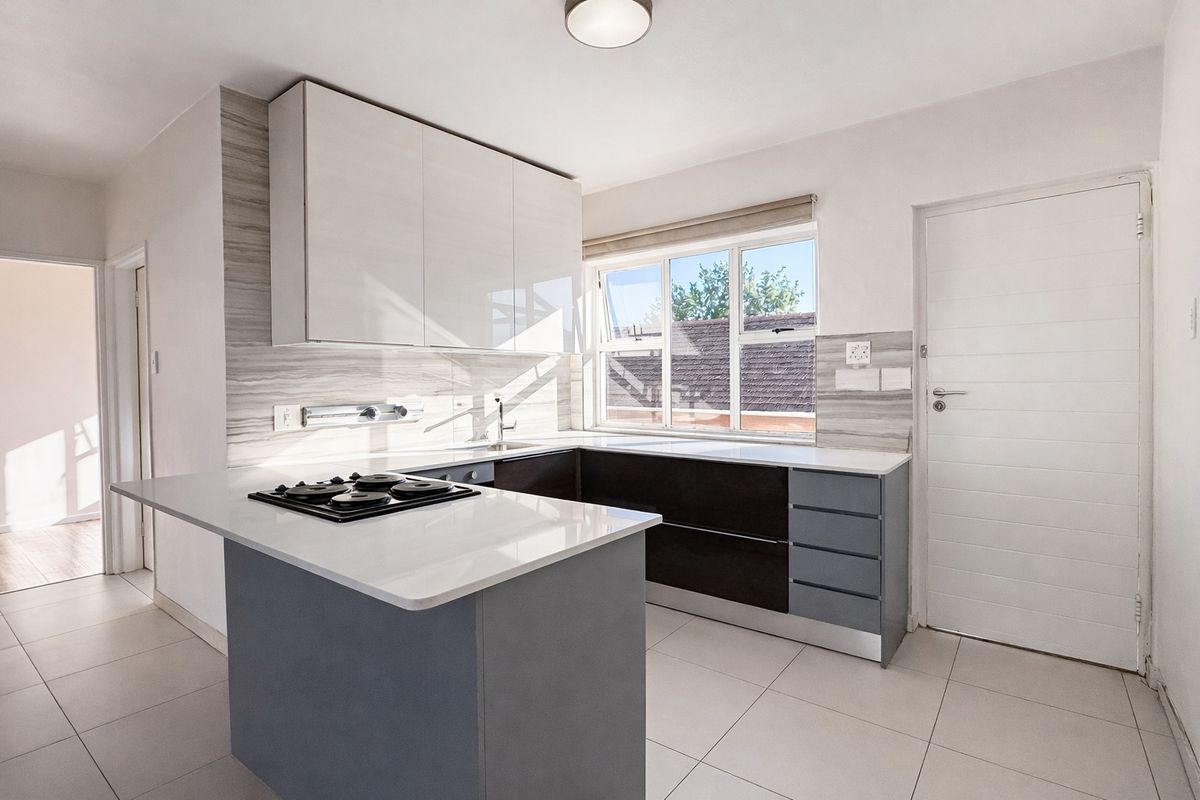 Modern kitchen featuring sleek cabinetry, stone countertops, integrated hob, and tiled flooring, offering a clean and functional workspace.