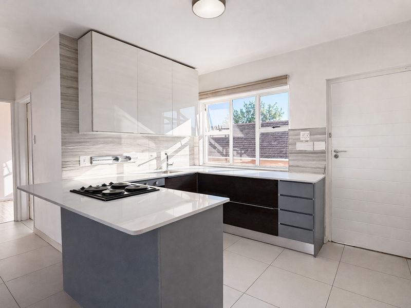 Modern kitchen featuring sleek cabinetry, stone countertops, integrated hob, and tiled flooring, offering a clean and functional workspace.