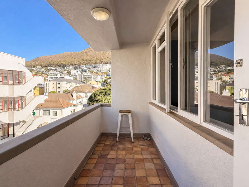 A covered balcony featuring tiled flooring, a ceiling light, and views of the surrounding neighborhood and mountain.