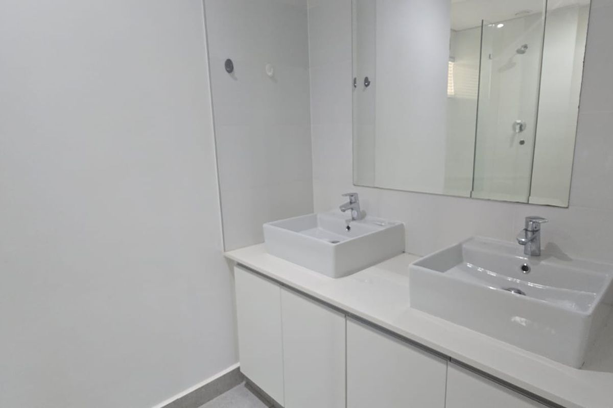 Modern bathroom featuring a double vanity with white vessel sinks, sleek cabinetry, and a large wall-mounted mirror.