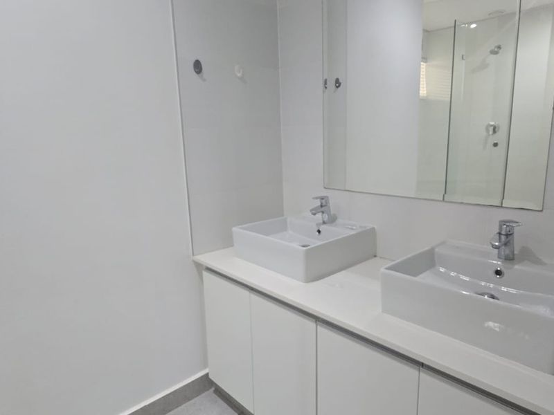 Modern bathroom featuring a double vanity with white vessel sinks, sleek cabinetry, and a large wall-mounted mirror.