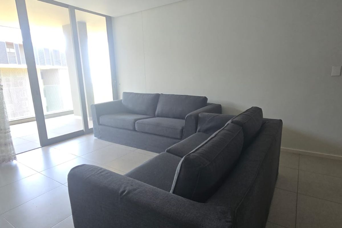 A bright living room featuring large floor-to-ceiling sliding glass doors that provide access to an outdoor balcony area and ample natural light.