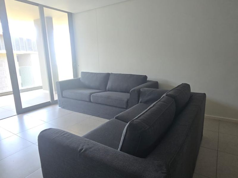 A bright living room featuring large floor-to-ceiling sliding glass doors that provide access to an outdoor balcony area and ample natural light.