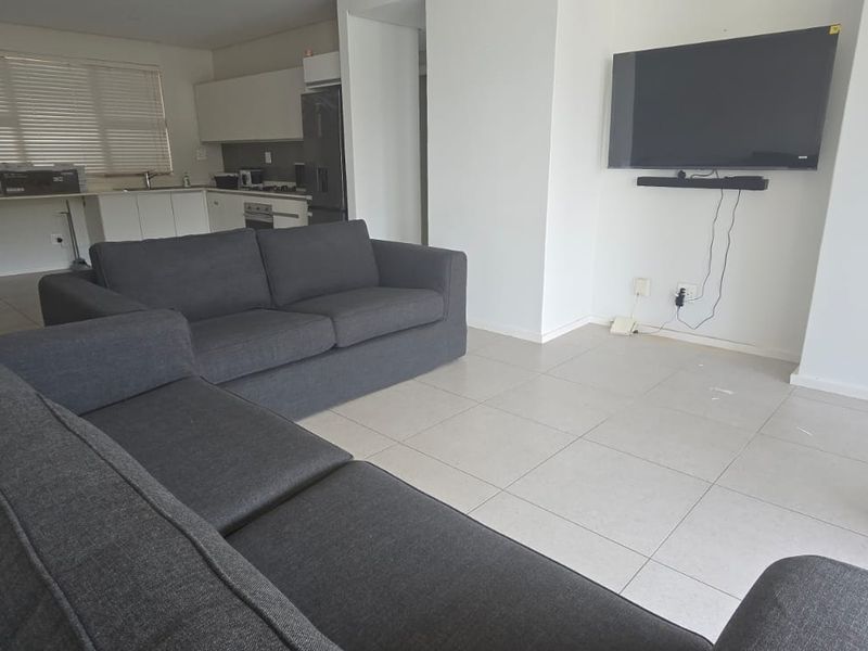 Open plan living area featuring tiled flooring and a modern kitchen with built-in cabinetry, seamlessly flowing into the lounge space.
