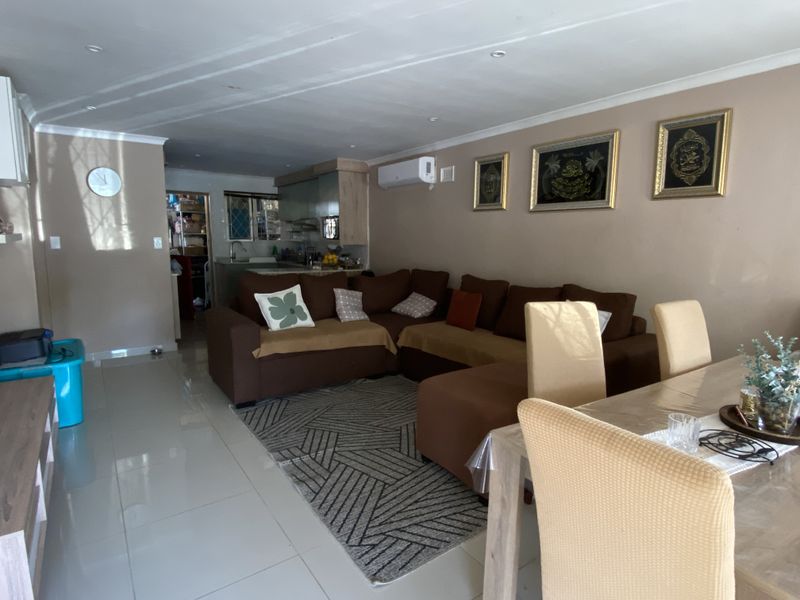 Open plan living and dining area featuring tiled flooring, recessed ceiling lighting, and a wall-mounted air conditioning unit.