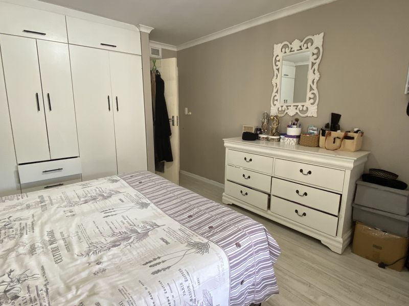 A bedroom featuring built-in floor-to-ceiling wardrobes and light-toned laminate flooring.