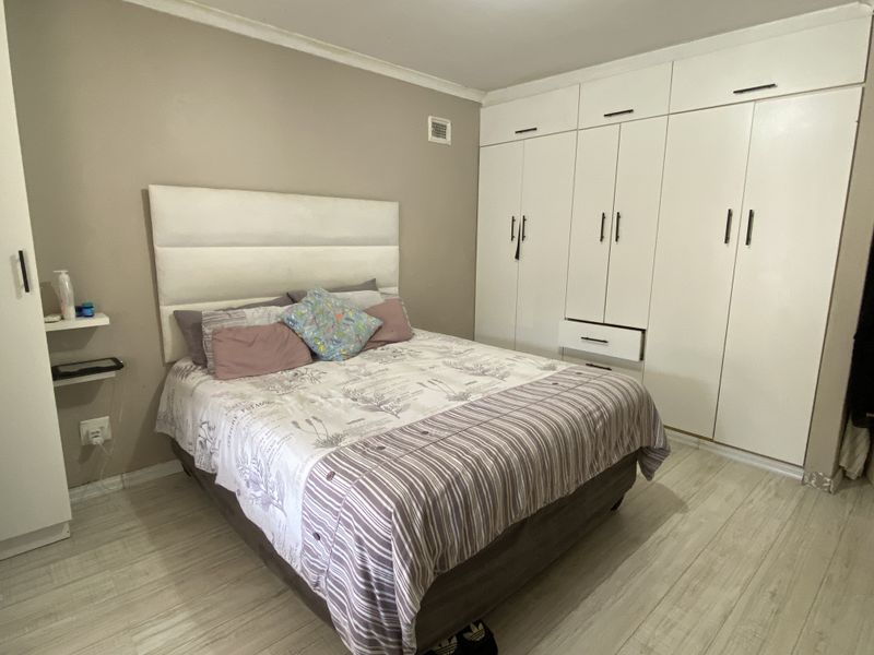 A bedroom featuring built-in floor-to-ceiling white cabinetry and light-toned wood-look flooring.