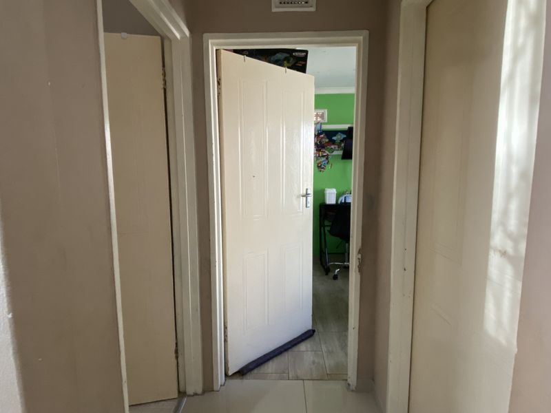 A narrow interior hallway featuring multiple internal doors leading to adjacent rooms, with tiled flooring and neutral wall finishes.