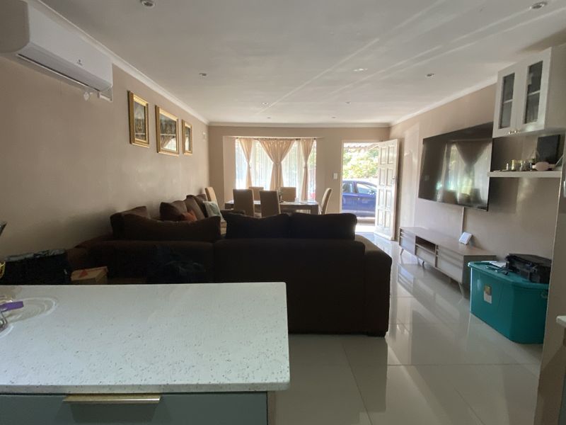Open plan living and dining area featuring tiled flooring, recessed lighting, and a wall-mounted air conditioning unit.