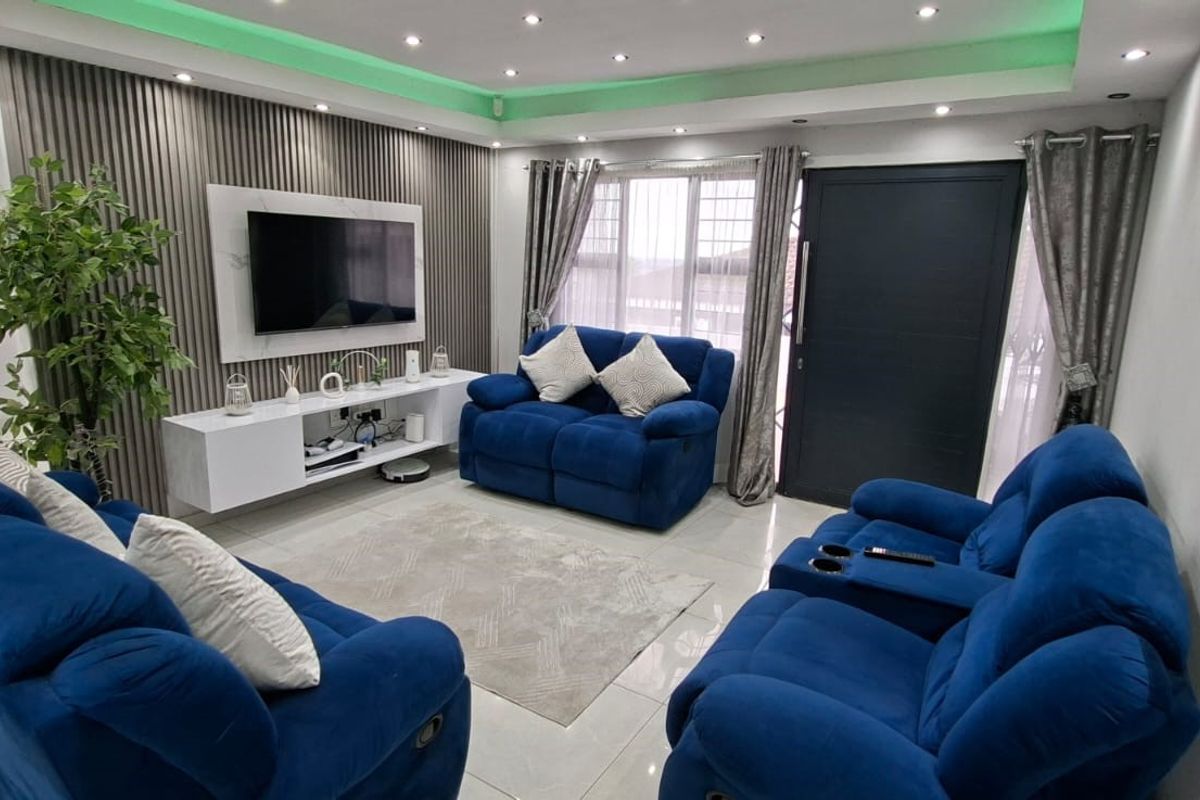 Modern living room featuring a decorative slatted feature wall, recessed ceiling lighting, and polished floor tiles.