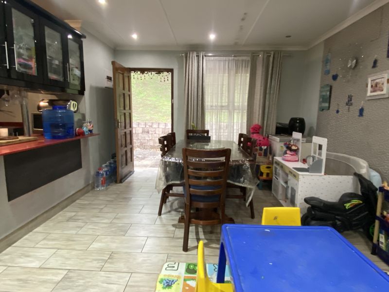 Open plan dining area featuring tiled flooring, recessed ceiling lighting, and direct access to the rear exterior through a wooden door.