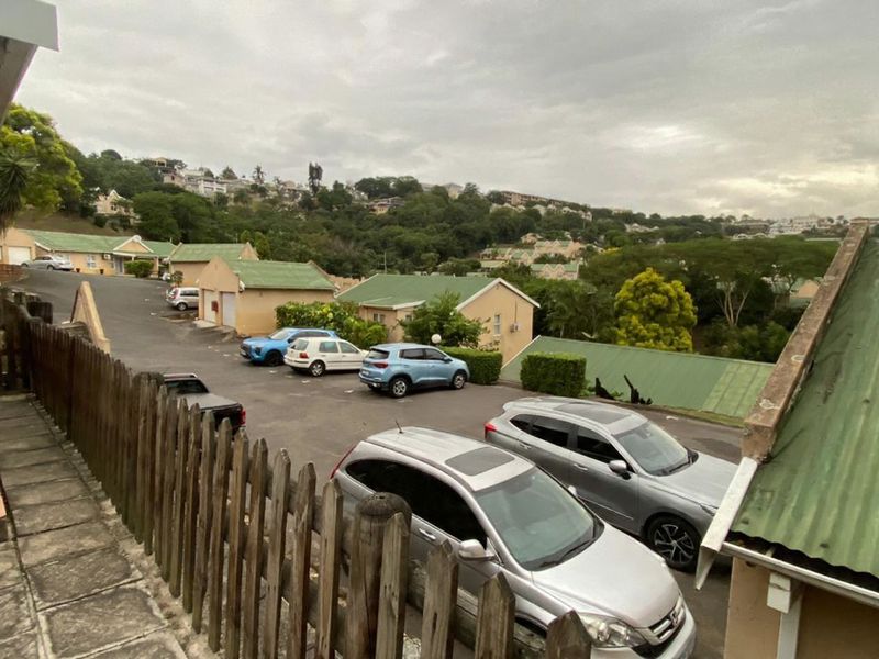 Elevated view overlooking a residential townhouse complex with paved parking areas and green metal roofing.
