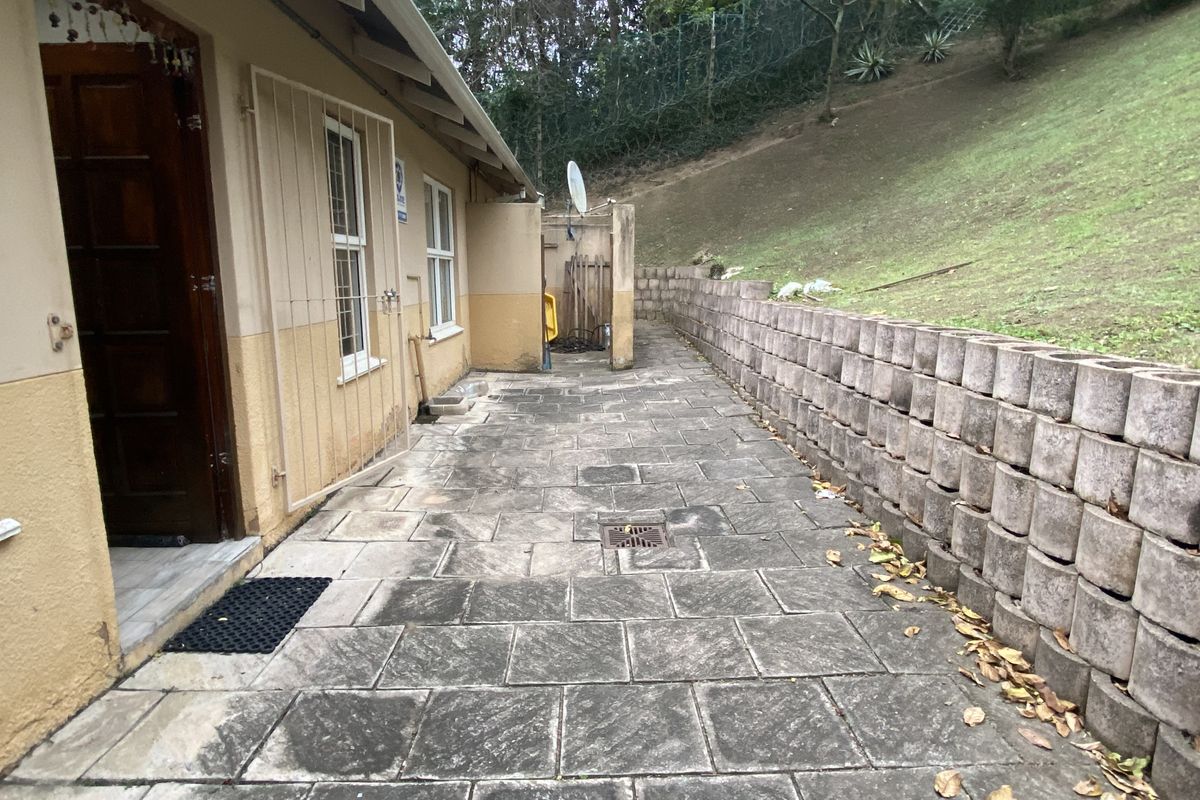 A paved rear exterior area featuring a concrete block retaining wall, security gate, and direct access to the townhouse.