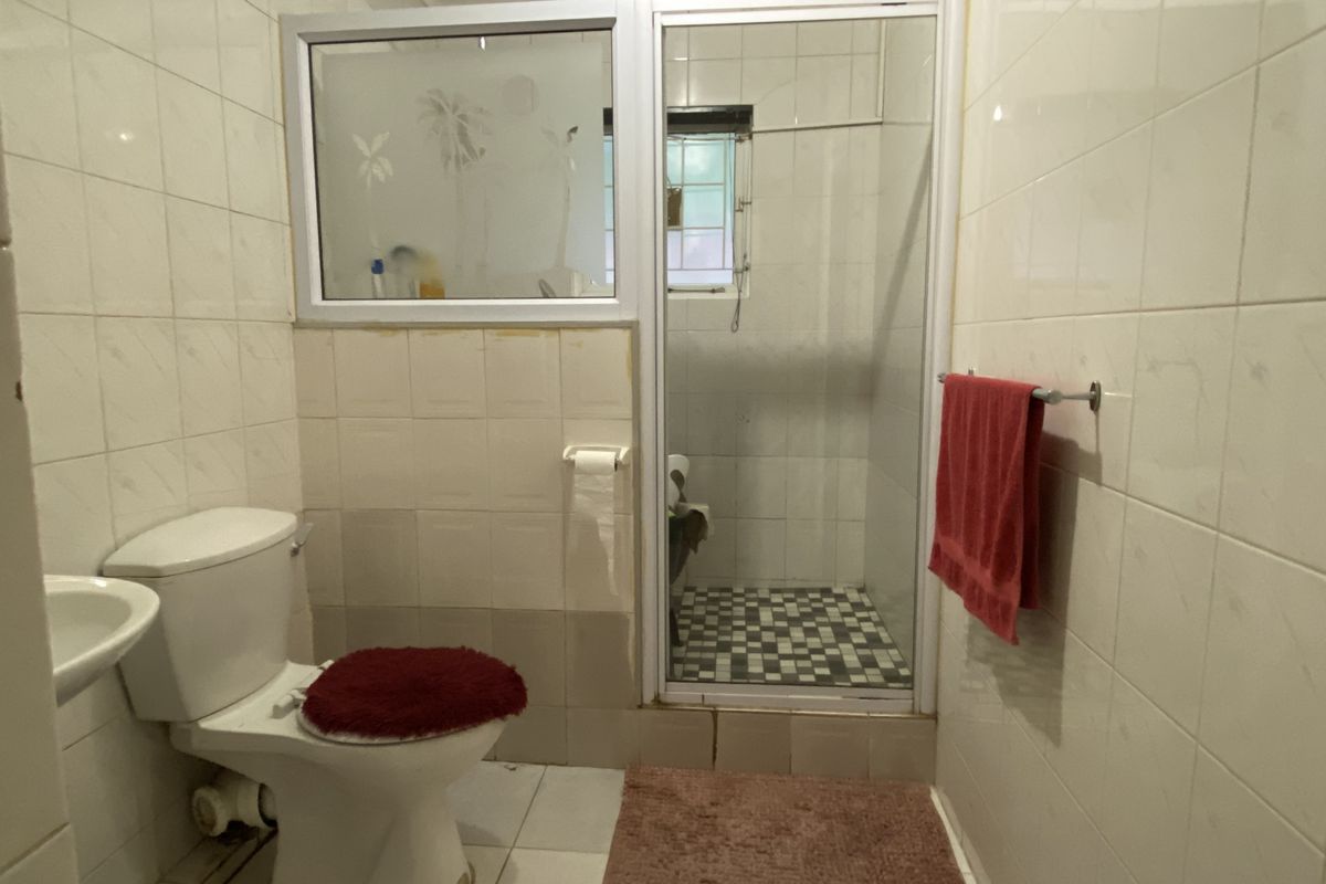 A functional bathroom featuring a walk-in shower with a glass enclosure, a standard toilet, and wall-mounted towel rail.
