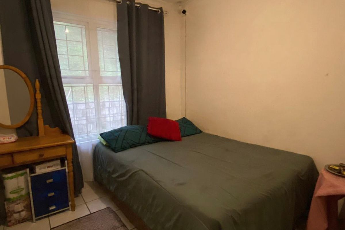 A functional bedroom featuring tiled flooring and a window with natural light, providing a comfortable space for rest.