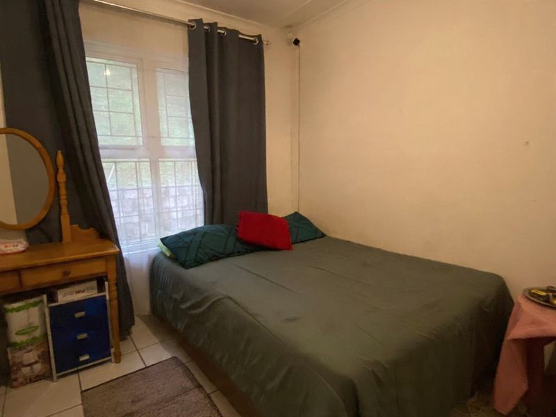 A functional bedroom featuring tiled flooring and a window with natural light, providing a comfortable space for rest.