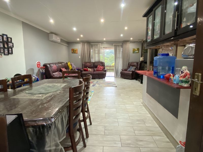 Open-plan living and dining area featuring tiled flooring, recessed ceiling lighting, and a breakfast bar counter, with direct access to an outdoor patio.