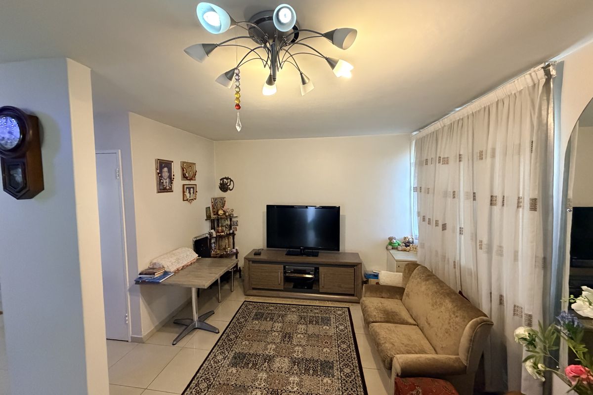 A well-lit living room featuring tiled flooring and a central ceiling light fixture, providing a comfortable and functional space for relaxation.