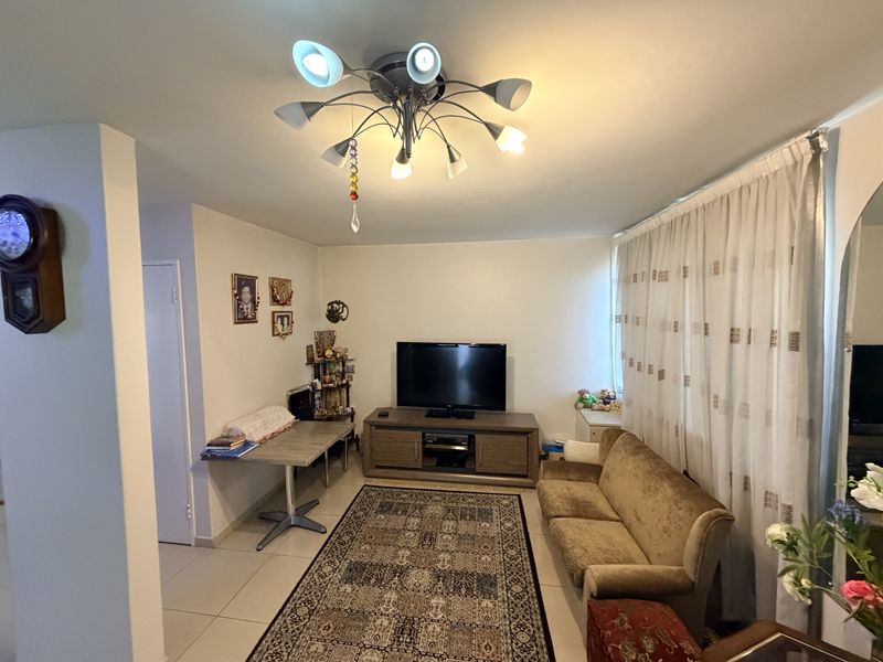 A well-lit living room featuring tiled flooring and a central ceiling light fixture, providing a comfortable and functional space for relaxation.