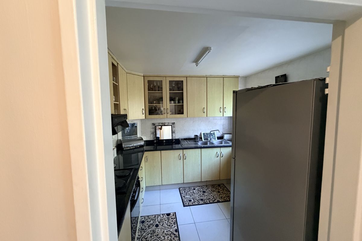 A functional kitchen featuring laminate cabinetry, granite countertops, a double bowl sink, and built-in cooking appliances with tiled flooring and backsplash.