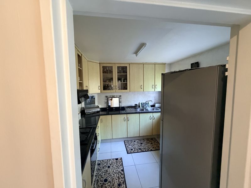 A functional kitchen featuring laminate cabinetry, granite countertops, a double bowl sink, and built-in cooking appliances with tiled flooring and backsplash.
