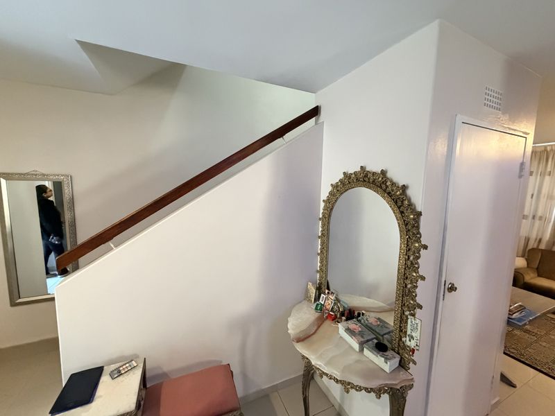 A bright hallway area featuring a staircase with a wooden handrail and access to adjacent rooms through a standard internal door.