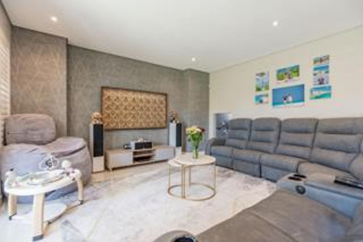 A comfortable living room featuring recessed downlighting, a textured feature wall, and neutral flooring, creating a functional and inviting space for relaxation.