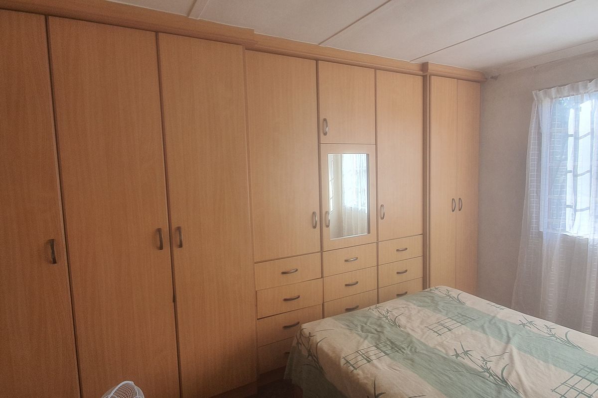 Bedroom featuring extensive wall-to-wall built-in wooden cupboards with integrated vanity mirror and storage drawers.