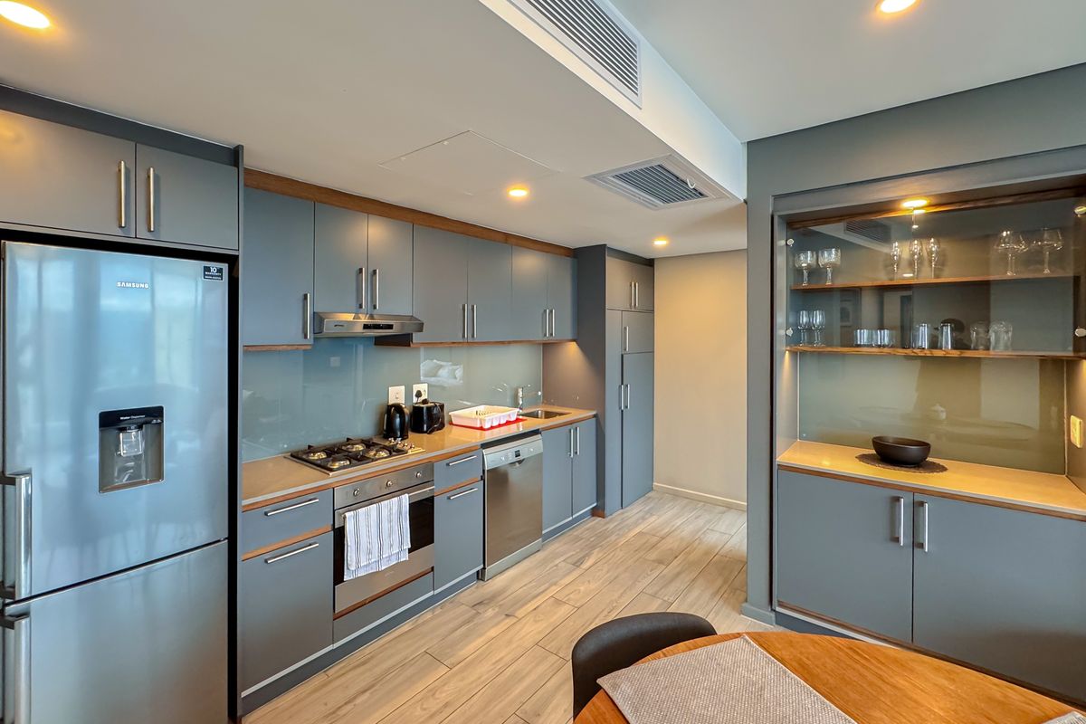 Modern kitchen featuring sleek grey cabinetry, integrated appliances, gas hob, built-in oven, and a dedicated display cabinet with glass shelving.
