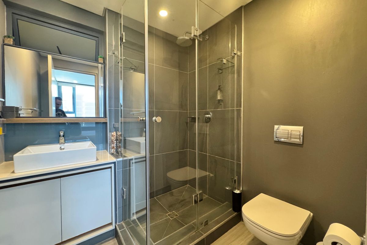 Modern bathroom featuring a glass-enclosed walk-in shower, wall-mounted toilet, and a contemporary vanity with a vessel sink.