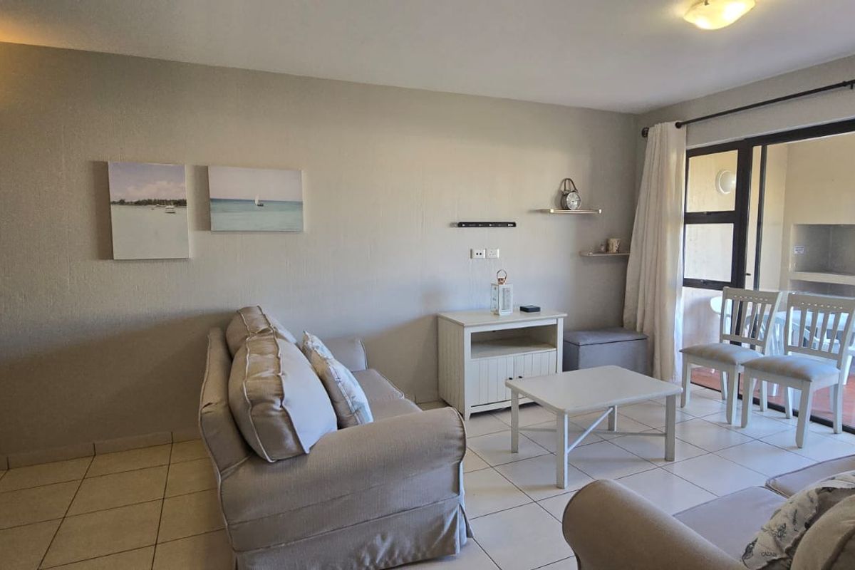 A bright living room featuring tiled flooring and large sliding glass doors that provide direct access to an outdoor patio area.