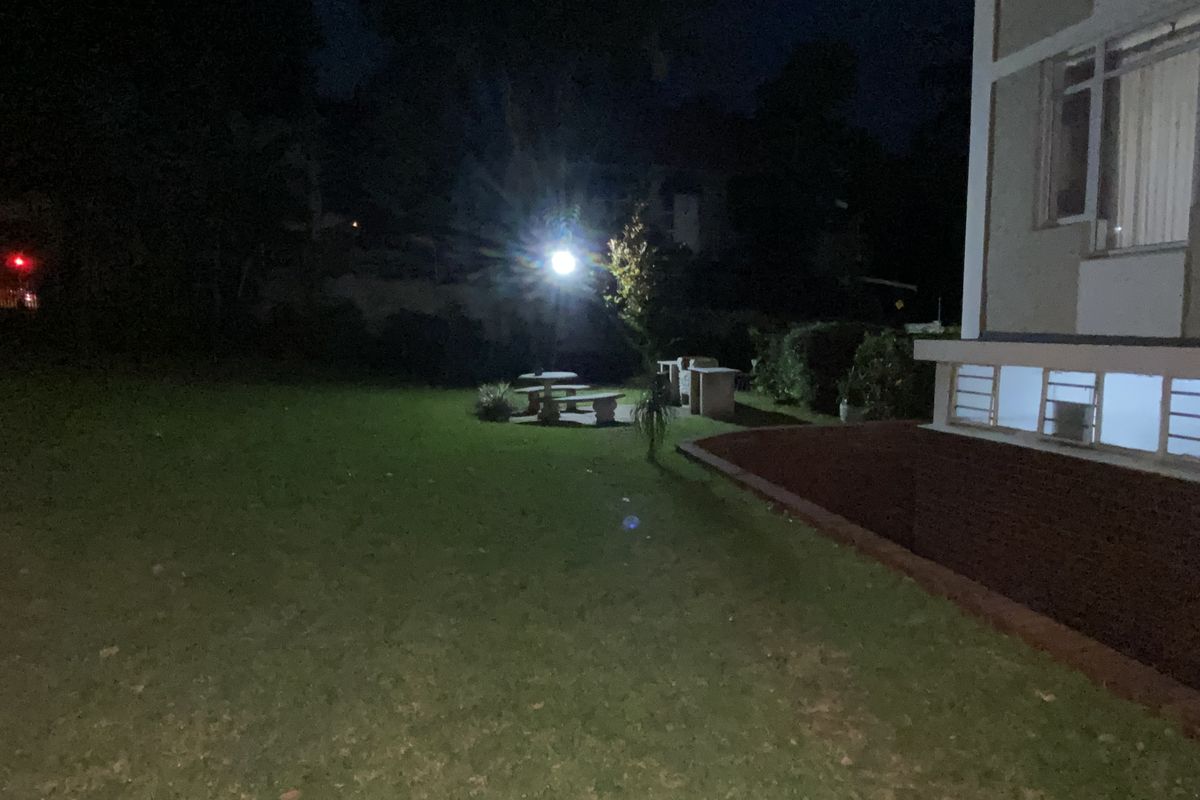 A night view of the apartment's rear garden area featuring a lawn and outdoor space adjacent to the building structure.