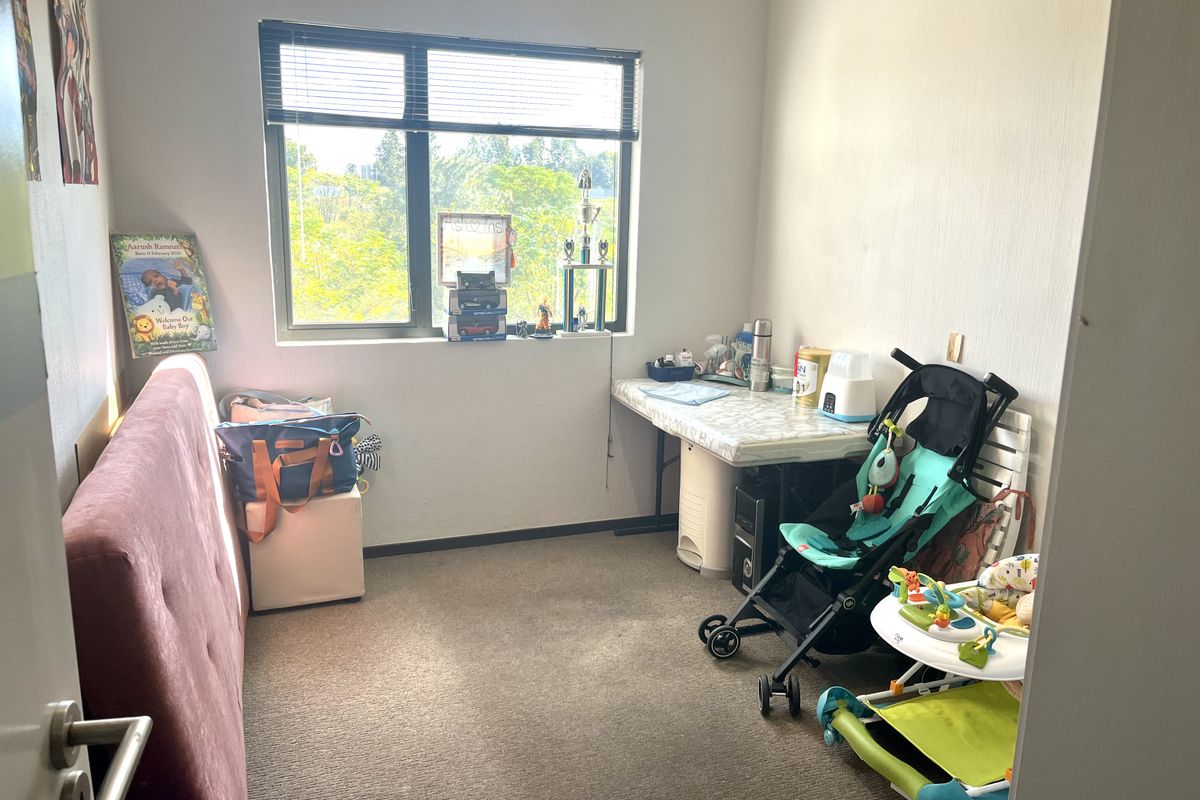 A bedroom featuring carpeted flooring and a large window with integrated blinds, providing natural light and an exterior view.