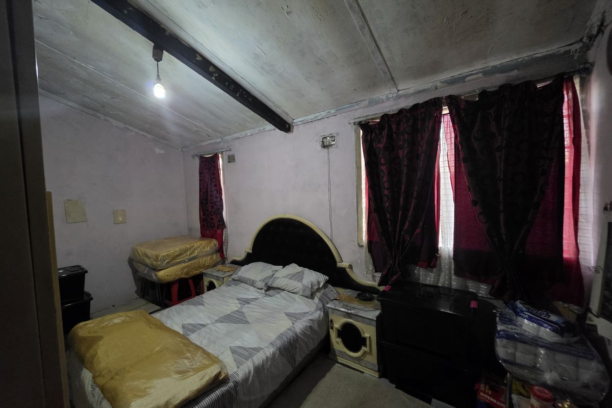 A bedroom featuring a sloped ceiling with exposed beam, requiring cosmetic updates and repairs to wall and ceiling finishes.