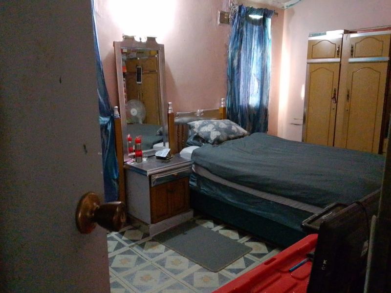 A bedroom featuring tiled flooring and a built-in wardrobe, requiring cosmetic updates to improve the overall aesthetic and condition of the space.