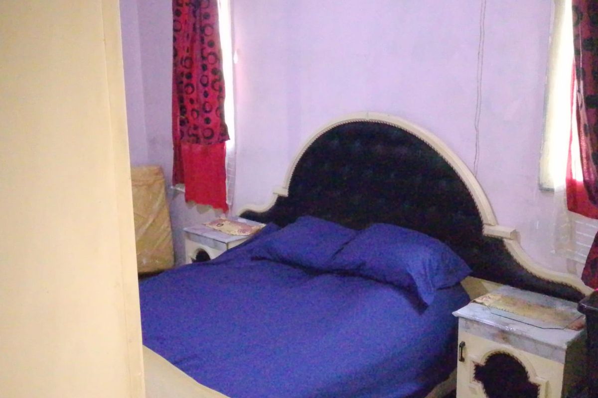 A bedroom featuring purple walls and a built-in electrical outlet, requiring cosmetic updates to improve the overall aesthetic and finish.