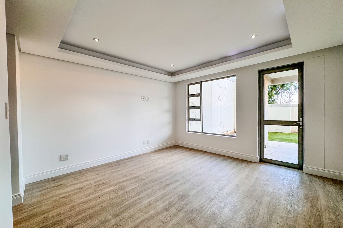 Bright and spacious living room featuring modern recessed ceiling lighting, wood-look flooring, and direct access to an outdoor patio area.