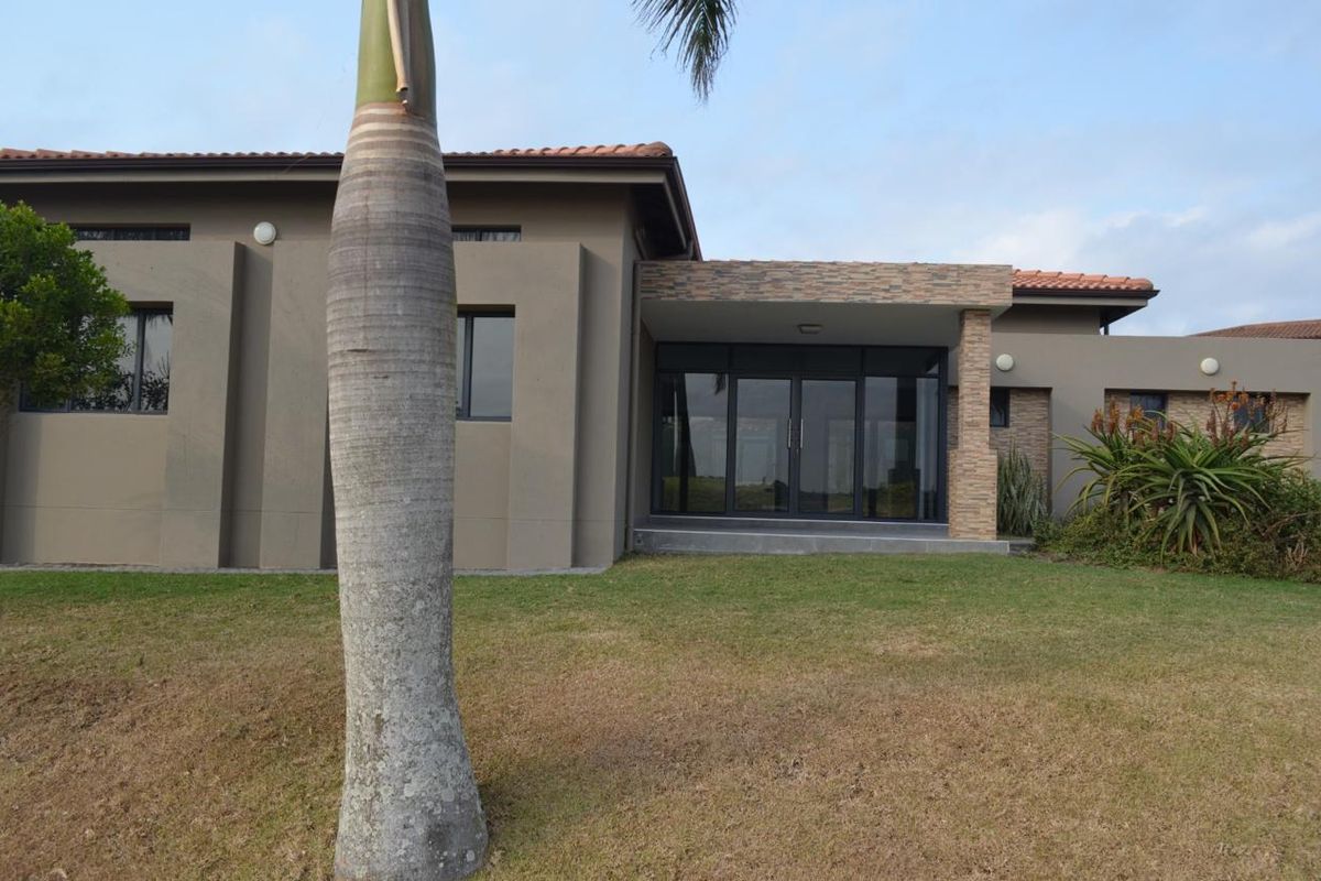A view of the rear exterior of the house, featuring a covered patio area with glass sliding doors and stone-cladding accents.