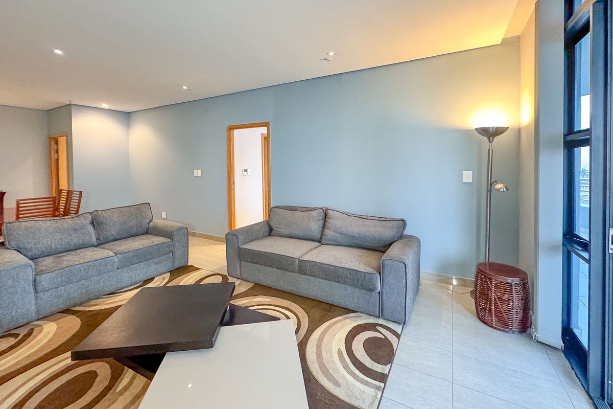 A spacious living room featuring tiled flooring, recessed ceiling lighting, and large glass sliding doors leading to an outdoor area.