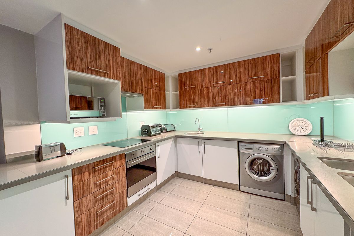 Modern kitchen featuring wood-grain and white cabinetry, integrated appliances, a glass splashback, and tiled flooring.