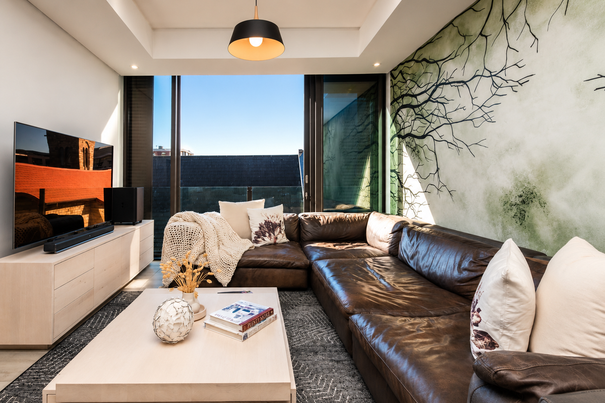 Modern living room featuring a tray ceiling, recessed lighting, and large sliding glass doors opening to a balcony with urban views.