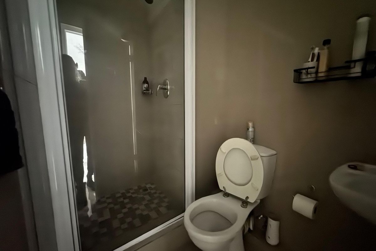 A functional bathroom featuring a glass-enclosed shower, a standard toilet, and a wall-mounted basin.