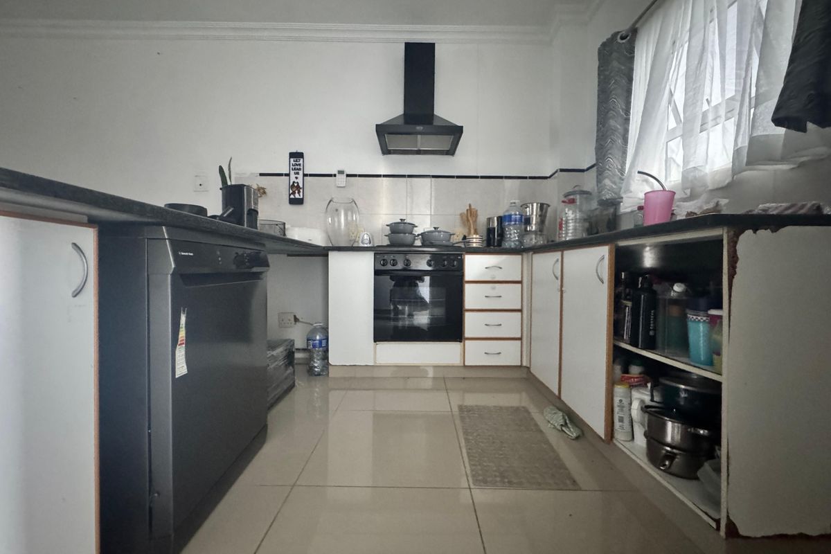 A functional kitchen featuring tiled flooring, built-in cabinetry, a black extractor fan, and an integrated oven, offering a practical layout for daily meal preparation.