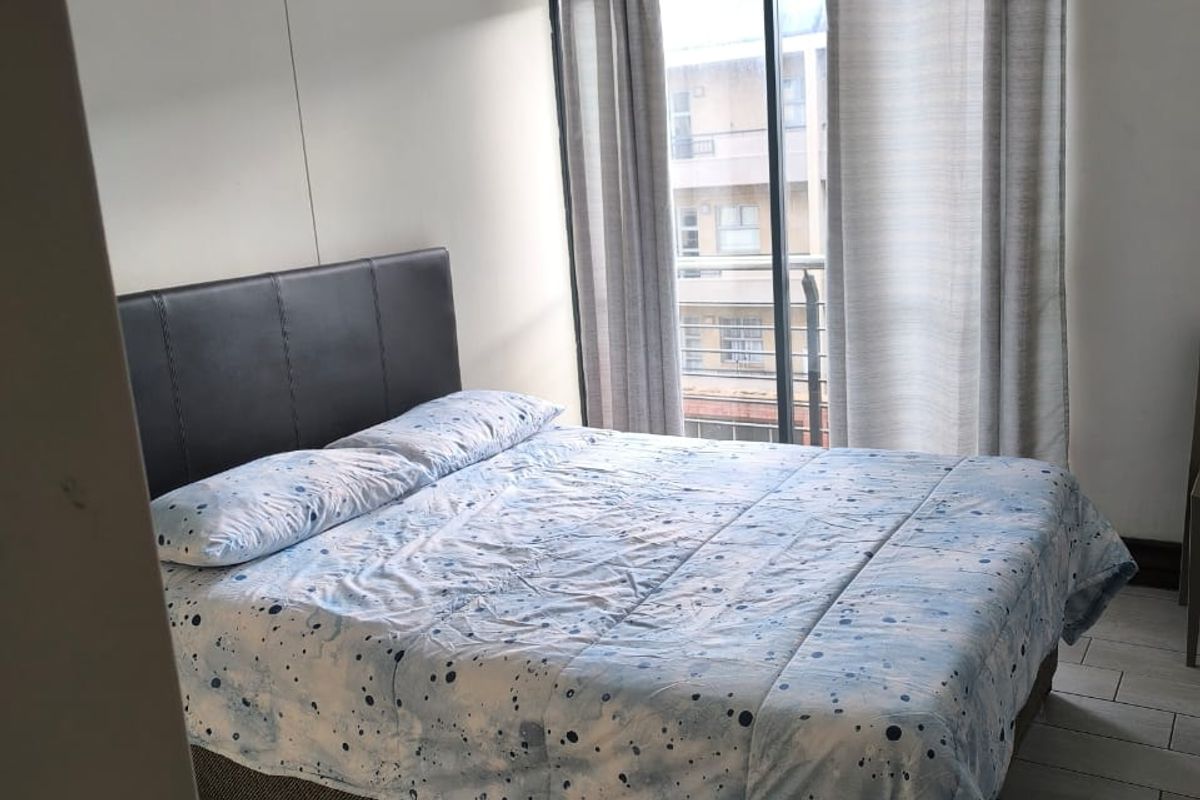 A bedroom featuring tiled flooring, crown molding, and a sliding glass door leading to a balcony.